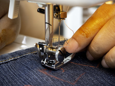 穿戴制造的概念。女性的双手在缝纫机上工作照片摄影